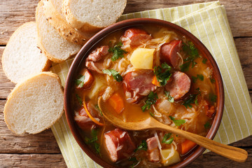 Wall Mural - Delicious soup of sauerkraut with sausages and vegetables close-up in a bowl. Horizontal top view