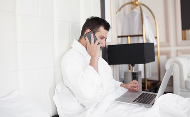 Man Eating Breakfast In Bed Whilst Using Mobile Phone