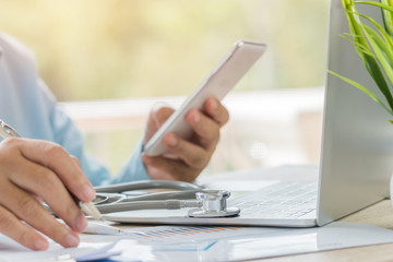 Wall Mural - Healthcare and medical concept, Doctor's working searching information about Patient database through internet computer and  Physician wearing Stethoscope on neck in hospital office, selective focus