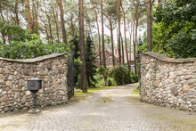 Entrance Gate To A Rustic, English House In The Forest With Stone Wall And Cobblestone Driveway