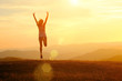 Happy woman with open arms jump on the peak of the mountain beautiful sunset background