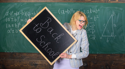 Wall Mural - Woman teacher formal suit holds blackboard inscription back to school. Lady educator in classroom prepare for new school year. Beginning of new school season. Teacher informs about start of education