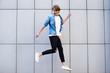 © MARIIA - Funky style. Handsome young man looking away with smile while jumping outdoors