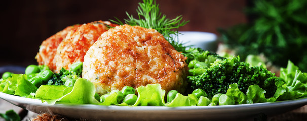 Fish cutlets or meatballs from cod and pike perch with a garnish of green peas and broccoli, rustic style, selective focus