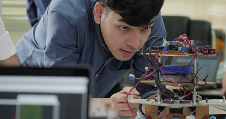Team of electronics engineer working together, collaborating on a project to build robot. People with technology or innovation concept.