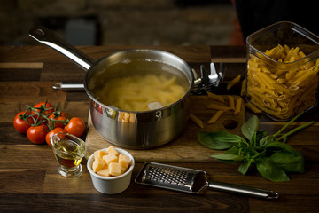 Wall Mural - Cooking penne pasta on the background of ingredients to sauce on a brick wall. Copy text recipe. Concept of Italian cuisine, selective focus