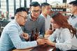 © DragonImages - Colleagues discussing photo on smartphone when resting in pub after work