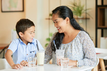 Cheerful Vietnamese Woman And Her Son Enjoying Milkshake In Cafe