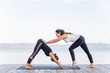 © Nichizhenova Elena - Young attractive smiling women practicing yoga on a lake