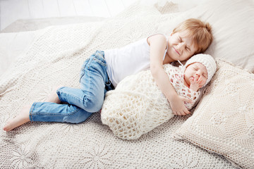 Portrait of newborn baby and elder brother. Young boy lying with newborn brother.