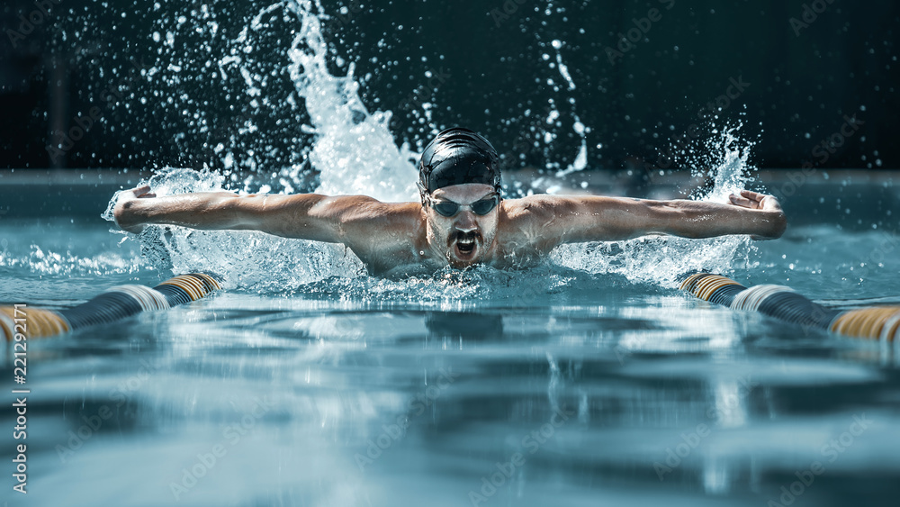 The dynamic and fit swimmer in cap breathing performing the butterfly stroke at pool. The young man. The fitsport, swimmer, pool, healthy, lifestyle, competition, training, athlete, energy concept - obrazy, fototapety, plakaty 
