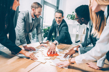 multiethnic businesspeople assembling puzzle together in conference hall