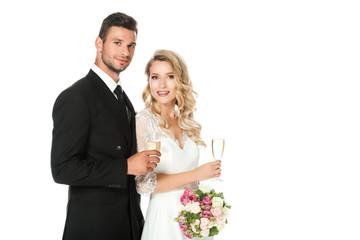 happy young newlyweds with champagne glasses looking at camera isolated on white