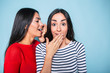 © My Ocean studio - Two beautiful brunette young girl friends gossiping in casual clothes over blue background