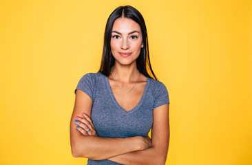 Wall Mural - Young attractive cute brunette woman in gray T-shirt is posing and looking on camera isolated over yellow wall
