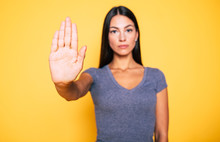 Stop Sign, Palm, Hand On Camera, Symbol - Don't Move. Close Up Photo Of Young Serious Woman Shows Her Palm Right On Camera Isolated On Yellow Background