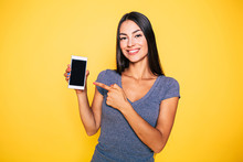 Choice It! Technology, Mobile, Equipment For Communication. Young Beautiful Woman Shows Right In Camera The Blank Screen Of Smart Phone On Yellow Background