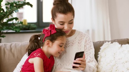 Wall Mural - christmas, technology and family concept - happy mother and little daughter with smartphone at home