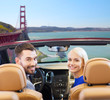 road trip, travel and people concept - happy couple driving in convertible car and looking back over golden gate bridge in san francisco bay background