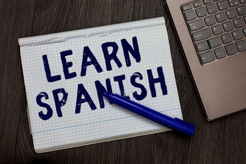 Conceptual hand writing showing Learn Spanish. Business photo text Translation Language in Spain Vocabulary Dialect Speech Open notebook squared page black marker computer wooden background