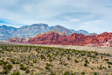 Bright Red Sandstone Rises Infront Of Tall Limestone Mountains In The Mojave Desert