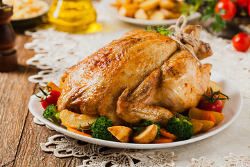 Wall Mural - Roast chicken whole. Served on a plate with vegetables and baked potatoes.