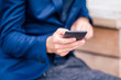 © travnikovstudio - Closeup of male hands is holding cellphone outdoors on the street. Man using mobile smartphone.