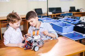 Wall Mural - Two brothers kids of different age playing with robot toy at school robotics class, indoor.