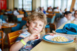 © Irina Schmidt - Cute healthy preschool kid boy eats pasta noodles sitting in school or nursery cafe. Happy child eating healthy organic and vegan food in restaurant. Childhood, health concept.