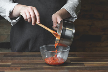 Cooking tomato sauce in metal saucepan by man cook hands, steps process on black background copy text recipe.