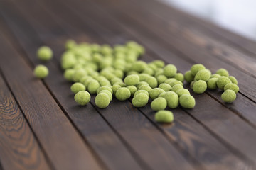 Peanuts with wasabi on wooden background, snack. Close up.