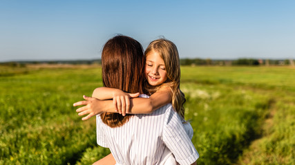 Wall Mural - mother embracing with her happy daughter in green meadow