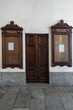 Antica porta con due antiche bacheche in vetro e legno per esposizione pubblicazioni di futuri matrimoni appese su una parete interna bianca in una chiesa