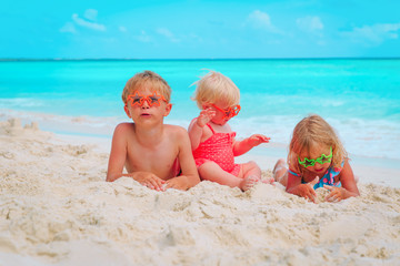 little boy and girls play with sand on beach