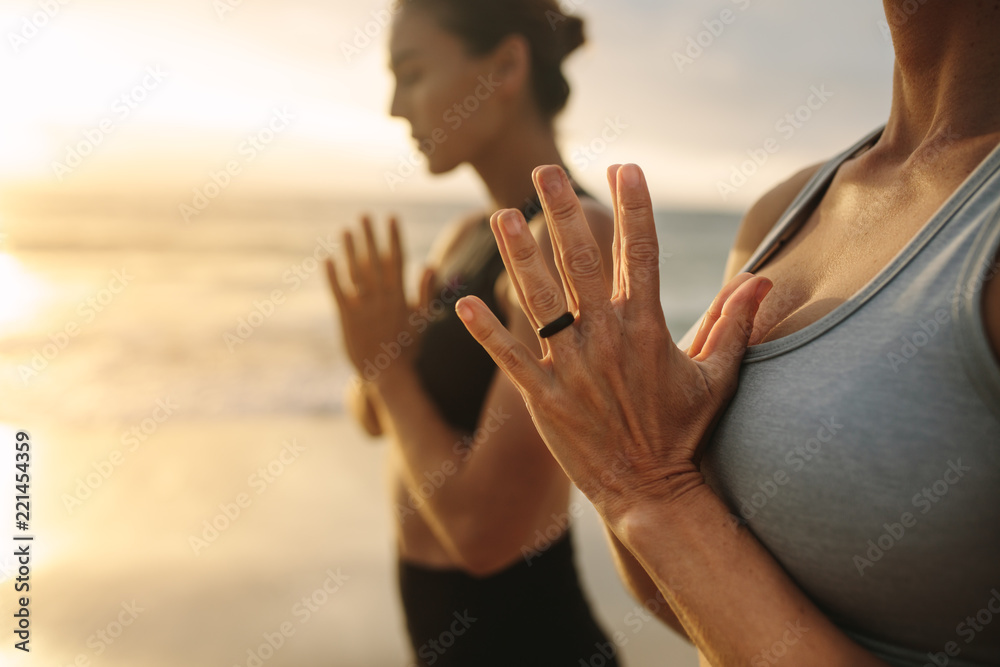 Women practicing yoga at the beach