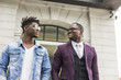 © xartproduction - two young and stylish African American men in the city smiling and talking. father and adult son relationship