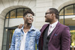 © xartproduction - two young and stylish African American men in the city smiling and talking. father and adult son relationship