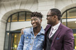 © xartproduction - two young and stylish African American men in the city smiling and talking. father and adult son relationship