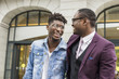 © xartproduction - two young and stylish African American men in the city smiling and talking. father and adult son relationship