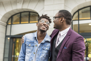 two young and stylish African American men in the city smiling and talking. father and adult son relationship