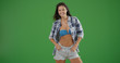Young woman posing in unbuttoned plaid and shorts smiling on green screen