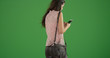 © Mark Adams - Rear view of young lady with smartphone texting on green screen