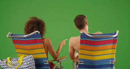 Wall Mural - Rear view portrait of couple sitting on beach chairs on green screen