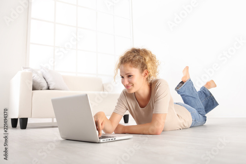 Smiling Beautiful Young Woman Using A Laptop Lying On Living Room