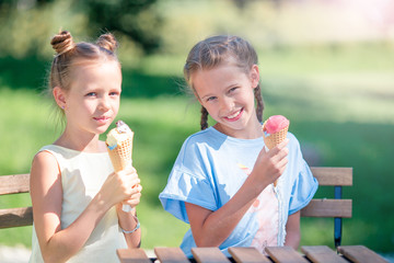 Little girls eating ice-cream outdoors at summer in outdoor cafe