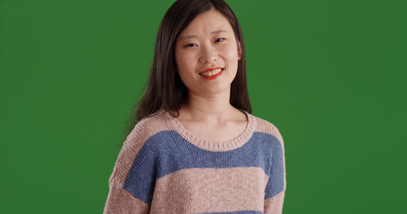 Wall Mural - Smiling Chinese female in sweater looking at camera on green screen