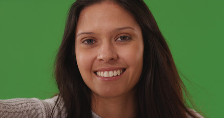 Portrait of smiling young lady looking at camera on green screen