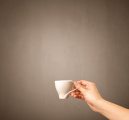 Young female hand holding coffee cup with brown background