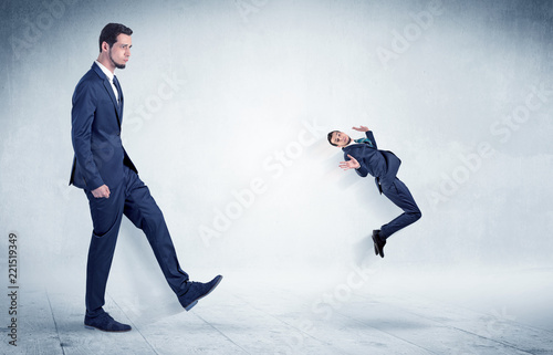 Fotografie, Obraz Big businessman kicking small businessman who is flying away with his briefcase