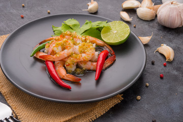 Wall Mural - Shrimps topped with seafood sauce on black dish.